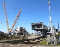 Ongoing work in connection with the upgrade of Port Talbot station, looking west from the level crossing on 2 October 2015. The large crane has recently lifted the first section of the new footbridge into place.<br><br>[Alastair McLellan 02/10/2015]