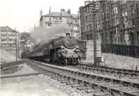 After emerging from the south portal of the tunnel from Crow Road in the summer of 1957, Standard Class 4 2-6-0 76101 has taken the left fork at Partick North Junction with a Maryhill - Rutherglen service. The train will already be slowing for its next stop at Partick West. On the right are the tenements of Maule Drive [see image 52289]. <br><br>[G H Robin collection by courtesy of the Mitchell Library, Glasgow 07/08/1957]