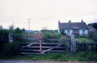 Looking north towards the station from the former level crossing on Station Road, Nethy Bridge in August 1985. The red diamond painted on the gate to warn motorists is fading, although it won't be closed over the road again ... [See image 24584] for a similar view when the gate was still in use.<br><br>[John McIntyre /08/1985]