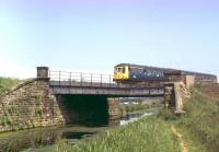 A Derby DMU, heading from Ormskirk to Preston, crosses over the Rufford Branch of the Leeds-Liverpool Canal in the summer of 1979. The scene is little changed today, other than the rolling stock in use on the Ormskirk shuttle. [See image 56346] [Ref query 7791]<br><br>[Mark Bartlett //1979]
