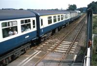 During the last summer of Saturdays Only London – Lowestoft trains for holidaymakers, a Class 47 hauled down working streaks across the level crossing at Bealings on the East Suffolk line. The photo was taken from the signal box window ledge on 20th August 1983. The crossing keeper was wary of some train drivers speeding on this stretch of line, having once watched his gates being “gone through” after his signals were overrun. The box was abolished the following Spring and the gates replaced by lifting barriers. [Ref query 6339]<br><br>[Mark Dufton 20/08/1983]