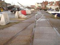 Looking seaward along the disused and disconnected tracks running along Whitby's Endeavour Wharf. The lines ran between the river and a large transhipment shed, enabling wagons to be loaded direct from seagoing vessels or from the shed itself. As the wharf has been out of use commercially for over a decade the goods shed has been demolished, and the cleared area is now used mainly for car parking. <br><br>[David Pesterfield 13/12/2015]