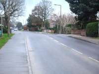 View south along New Road at Huntington on the outskirts of York showing the significant hump just before the entrance to the Shepherd Group Portakabin production plant. A level crossing existed here on the York to Beverley line, closed 50 years ago in 1965. Earswick station was sited a short distance to the right, towards York, with Warthill the next station to the east. The former trackbed beyond the grassed area to the left, along the northern boundary of the Portakabin plant, forms a long linear car parking area. [See image 53739]<br><br>[David Pesterfield 22/12/2015]