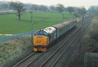 Despite having left Carlisle over four hours earlier at 0515hrs, and travelling via the circuitous (and multi-stop) Cumbrian Coast route, 37401 is <I>Right Time</I> passing Woodacre on 4th January 2016. The large-logo <I>Mary Queen of Scots</I> is propelling its four coaches on the short sprint to journey's end at Preston. <br><br>[Mark Bartlett 04/01/2016]