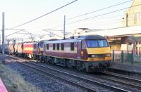 A pair of red and gold DBS Class 90s take the Dollands Moor to Irvine china clay tanks through Carnforth on 20th January 2016. 90020 <I>Collingwood</I> is working in multiple with 90039 but, due to the ongoing Lamington viaduct repairs, they will be replaced by diesel traction at Kingmoor rather than Mossend. <br><br>[Mark Bartlett 20/01/2016]