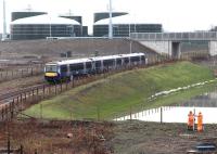 Two men comparing sticks alongside the attenuation pool of the Edinburgh and Midlothian food waste recycling plant at Millerhill on 19 January 2016. In the centre background ScotRail 170475 is about to pass below the bridge linking the main plant with Whitehill Road. Note that the lifebelt is attached to the perimeter fence, not the train.<br><br>[John Furnevel 19/01/2016]