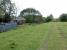 View west at Wellwood Siding Cottage (seen to the left). This was to the east of the A70. Wellwood No 3 Pit Signal Box (Wellwood No 1 Signal Box which was further east) was in front of the cottage and to the left of the trackbed. It controlled access to a siding.<br><br>
<br><br>
This siding was one of two which gave access to the Nether Wellwood pits by reversal. One of these is to the left (it survived closure of No 3 pit and double tracking of the railway and must have been retained as a refuge) and the other is some way behind the camera to the right (it served No 2 pit). The latter siding closed on double tracking of the Muirkirk line and was replaced with a short lived private line from Muirkirk Ironworks.<br><br>
<br><br>
The bing to the left was in an area of old bell-pits which had been served by an early waggonway from the Muirkirk Ironworks. The same pits may have served the Nether Wellwood Ironworks of the 1730s.<br><br>
<br><br>
The cottage was abandoned shortly before the photograph was taken, due to the expansion of the Powharnal opencast into this area which has destroyed the remains of everything described above - at the time of writing this view would be of a large flooded hole in the ground.<br><br>[Ewan Crawford 25/06/2003]