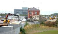 Site of Granton Gasworks in 2006, with the Edinburgh & Leith Gas Commissioners 1902 station building and platform still intact. The line ran alongside the wall through what was originally an open structure (now bricked up at both ends), with the platform connected by an internal stairway to the upper level. From there a footbridge spanned the sidings to access the works and offices off to the left. The new Scottish Gas HQ stands in the background beyond the station. [See image 10312]<br><br>[John Furnevel 16/08/2006]