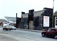 Riccarton & Craigie station entrance and bridge abutments (station had an island platform), looking southwest from across Campbell Street in Riccarton, Kilmarnock, 20 October, 1985. Although this station was completely erected, including buildings, it never opened to regular passenger services, if at all. The twin bridges had been removed in the early 1970s (or thereabouts), and the rest of the railway relics were about to be demolished in the name of progress; the A71 bypass was about to be built on the trackbed through here.<br><br>[Robert Blane 20/10/1985]