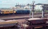 View across Lesmahagow Junction with a ballast train in the foreground reversing into the Findlays Sidings. In the background is 37140 with a permanent way train and the buildings of the Motherwell Bridge company.<br><br>[Ewan Crawford //1988]