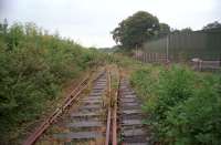 Cwm Mawr in September of 2002 looking north to the terminus from the level crossing. The line closed to goods in 1996. There are plans to preserve the line and much of the track remains between Kidwelly and Cwm Mawr, albeit very overgrown. Some level crossings have been rebuilt with the track either buried under tarmac or lifted. The sign seen in Andrew Saunders' photograph still exists, just off to the right of this view.<br><br>[Ewan Crawford /09/2002]