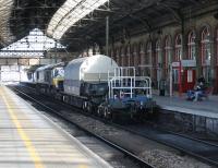 A 16 wheel (4 bogie) MOD wagon trundles north through Preston station behind DRS 66424 on 14th March 2016.<br><br>[Mark Bartlett 14/03/2016]