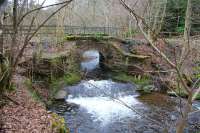 Route of the Penicuik Railway shortly after leaving Eskbridge station (off picture to the left) heading for Auchendinny. This bridge carried the line over the Loan Burn, which enters the River North Esk immediately behind the camera.  View is west on 28 March 2016, nearly 50 years after closure.<br><br>[John Furnevel 28/03/2016]