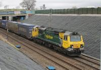 The recently upgraded cutting at Hampson Lane near Galgate has the appearance of a brand new railway. Freightliner 70011 is on a Coatbridge to Daventry service on 4th April 2016. This is timetabled for electric haulage but has been using Class 70s recently. The bridge in the background carries the motorway slip roads at Junction 33 of the M6. <br><br>[Mark Bartlett 04/04/2016]