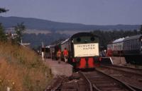 Inveresk Paper Hudswell Clarke 0-4-0 shunter is stabled on the down platform at Boat of Garten during the hot summer of 1975. A work party take a break from digging in a set of point rodding cranks and head along the platform to get some refreshment.<br><br>[John McIntyre 10/08/1975]