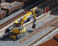  A Road/Rail vehicle scoots up and down the newly-laid track of the platform 5 road with its grab full of ballast for topping up in the 'six-foot'. Behind it, sleepers laid out for the platform 6 track await the arrival of their rails. The ballast train is on the platform 7 road, where the old track remains.<br>
<br><br>[Colin McDonald 02/05/2016]