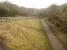 Looking south from Grange Lane overbridge near Cotham village along the trackbed of the former Newark to Bottesford line in March 2016. The view shows the limit of the hard surface of the combined footpath and cycle route 64 that runs from east of London Road at Balderton to this point. Beyond the bottom of the access ramp the trackbed becomes overgrown, although there is a narrow walked track continuing south.  <br><br>[David Pesterfield 16/03/2016]