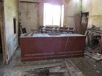 A photograph taken inside the station building showing the remaining furniture in the booking office.<br><br>[Clive Meredith /06/2015]