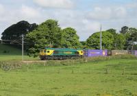 Freightliner 66528 <I>Madge Elliott MBE</I> hauls the late running Coatbridge Daventry service towards the Oubeck Loops on 23rd May 2016. The container train is just about to cross the Burrow Beck. This rural scene is set to change as the land on this side of the railway is earmarked for a retail development. [See image 51530] <br><br>[Mark Bartlett 23/05/2016]