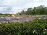 Looking over the concrete pad being created by Balfour Beatty on a works site near the former Haigh Station, standing in the centre background. The pad will provide a solid base to facilitate construction of a new bridge deck to replace the 3.4m high and single lane arched skew bridge, off picture to right, over Haigh Lane; and provide around 300mm of extra headroom.<br><br>[David Pesterfield 19/05/2016]