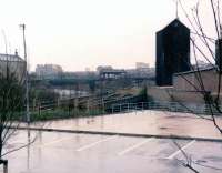 A view west towards Partick Central station from the car park of the Kelvin Hall on a very wet spring day in the early 1980s. The plate girder rail bridge over the River Kelvin is centre left, with the station booking office on Benalder Street in the middle distance.<br><br>[John McIntyre //]