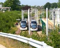 Trams for Edinburgh Airport and York Place call at the staff halt alongside Gogar tram depot on 7 June 2016 for crew changes. View is west towards the airport with the A8 on the left. [See image 50467]<br><br>[John Furnevel 07/06/2016]