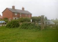 View east on 1 September 1990 of a long redundant complete crossing gate installation on the west side of Browns Terrace in Hinderwell village, on the Whitby to Loftus line. In the right background are the roof and chimney of the yard office by the coal drops alongside the A174 coast road [See image 27126], whilst on the left are 1-4 Railway Cottages. The crossing gate is still in situ as of June 2016. <br><br>[David Pesterfield 01/09/1990]