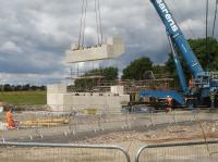 The first cast on site abutment for the replacement bridge across Haigh Lane can be seen part way through the transfer from casting position onto one of the two heavy duty trestles seen beyond the 750 ton lifting capacity crane. Once both abutments are in correct position the deck will be added and all bolted up. Work will then continue to create a fully complete bridge unit able to be placed onto prepared footings, and ready for ballast and track to then be laid across it. The replacement works have to be completed in a 52 hour possession in early August. <br><br>[David Pesterfield 14/07/2016]