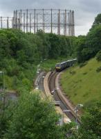 View over Kelvindale Station with a Glasgow Queen Street - Dundee<br>
approaching.  The gasholder frames of Dawsholm Gasworks dominate the<br>
skyline.<br><br>[Bill Roberton 18/07/2016]