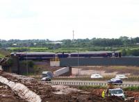  The 0944 Glasgow - Inverness service, unusally a Class 158 unit and diverted to start from Glasgow Central due to the Queen Street High Level Tunnel works, is seen passing over the Bargeddie bridges just over a year after the M8 viaduct opened. The temporary embankments used in construction have long gone and the carriageways of the new M8 extension now run under the viaduct. The distinctive steelwork of the beginning of older 'Cutty Sark' bridge can just be seen on the left above the earthworks of the A8 realignment now under construction.<br><br>[Colin McDonald 29/07/2016]