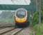 A London bound Pendolino passes Euxton on 11 June 2016. Euxton Jct is behind the train to the left as it crosses a minor road on structure 89. The footbridge behind is structure 90.<br><br>[John McIntyre 11/06/2016]