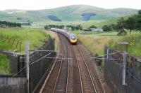 The 1200 Glasgow Central - London Euston, having just passed Crawford, and the country's largest IT advert, is about to run below the A702, from which the photograph was taken. Less than 50 yards further on it will pass below the A74(M). In the foreground are the remains of the bridge that once carried the original road.<br><br>[John Furnevel 27/07/2016]