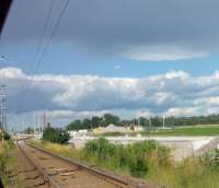 View of the existing sinuous single track route looking north east at Samnan level crossing north of Gamla Uppsala. The new double track alignment can be seen as the pale grey construction curving in from the right. The reason for the odd arrangement is that a new underbridge has been opened which was designed to fit on the new alignment and this is less than ideal for the current alignment which has remained open for low-speed train movements throughout the construction period.<br><br>[Charlie Niven 05/07/2016]