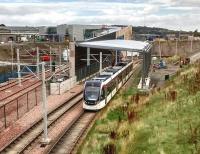 On 1 September 2016 an Airport-bound tram passes what will soon be another stop and interchange with the ScotRail station behind. The tramstop will be the only one with an overall roof. The tracks on the left lead to Gogar Tram Depot. This location is just outside the edge of built-up Edinburgh, but as it's Green Belt I don't think we can expect the stations to become a locus for development. It's also a bit noisy here, being next to a very busy junction on the A8.<br><br>[David Panton 01/09/2016]