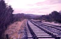 Track lifting had started on the former Highland line north of Boat of Garten in December 1973. With the North SB behind the photographer, the original track recovery had stopped at the north loop points. With the council wanting to widen the road under the railway near to this point the Strathspey Railway recovered the track and the bridge was demolished in June 1974.<br><br>[John McIntyre 29/12/1973]