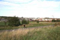 A Sunday morning stroll along the old Waverley Route at Hardengreen on 15 October 2006. View is north east, with the Tesco Superstore in the background. The lady and her dog are passing the site of the planned Eskbank station, albeit some 30 feet above it. [See image 47159]<br><br>[John Furnevel 15/10/2006]