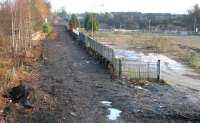 Looking east in January 2006 over what would become the new Alloa station. At this stage the old track has been lifted and the trackbed partially cleared, although some imbedded rails remain beyond the gate which accessed the former brewery complex. Plant and equipment began to move onto the site the following month, with various follow-on developments including new housing off to the left and a supermarket on the right. [See image 23899]<br><br>[John Furnevel 24/01/2006]