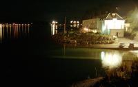 The former Highland Railway Lochalsh Hotel at night in 1993 with the slip in the foreground. The ferries had stopped for the night and were tied up at the station pier. Beyond the hotel is the under construction Skye Bridge and, to the left, Kyleakin.<br><br>[Ewan Crawford //1993]