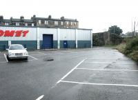 The site of Rosebank goods yard looking south east towards Bonnington Toll on a Sunday morning in October 2002, with the area occupied by retail units and a car park (although plans were already in course to replace these with a large block of flats). The goods depot occupied the area to the left, while the Caledonian line continued on its high level route towards Leith East via the bridge over Bonnington Toll, the surviving abutment of which still stands in the background [see image 57249].  <br><br>[John Furnevel 06/10/2002]