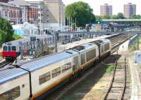 A Eurostar runs south ecs through Kensington Olympia on a pleasant July morning in 2005, on its way from North Pole depot to Waterloo. Over on the left a District Line train is getting ready to leave the bay platform on the short trip to High Street Kensington. Note the spare power car bringing up the rear of the Eurostar. <br><br>[John Furnevel 21/07/2005]