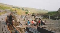 A general view of the reconstructed railways at Killhope Mine high in the Upper Weardale hills. In the left foreground is what might be called a 'beamway' with flat iron-covered wooden rails supported on beams. Running on this are waggons with flanged wheels. Below, running off into the distance, is a more conventional narrow gauge edge railway with smaller waggons. At that time the museum was relatively undeveloped compared to the present award-winning multi-themed attraction.<br><br>[Charlie Niven /06/1994]