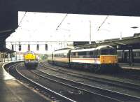 A down WCML service arrives at Carlisle platform 3 in August 1997 behind BR InterCity liveried 87014 <I>Knight of the Thistle</I>, complete with matching set. Held at signals on the centre road is an EWS class 37 with a lightweight freight.<br><br>[John Furnevel /08/1997]