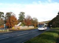 The 1000 Edinburgh – Hawick First Bus runs through the site of Lindean station on a fine autumn morning in November 2016. The level crossing has been replaced by crossroads, although the surviving station house still stands immediately beyond the fence. [See image 57246]<br><br>[John Furnevel 10/11/2016]