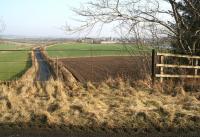 Standing on the trackbed above the bridge at the north end of Charlesfield Halt in February 2017, looking east along the unclassified road leading to the former munitions depot, visible in the background.  <br><br>[John Furnevel 14/02/2017]