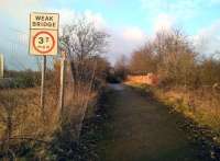 Sadly, this road over rail bridge is the only relic of the once extensive layout of Towcester station. It took the old Tiffield road over the Olney branch, but is now only a footpath; making the weight limit sign somewhat insulting to pedestrians. The wooden pole just visible across the bridge marks the point from which I took my previous image [see image 27910]<br><br>[Ken Strachan 10/02/2017]