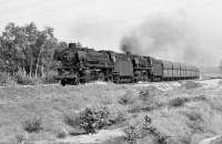 A 4,000 tonne iron-ore train from the docks at Emden passes Hanekenfaehre (near Lingen) at 10:21 on Saturday 7 September 1974 and enters the single track section over the River Ems. Motive power consists of oil-fired 2-8-2 No. 042 241 and coal fired 2-10-0 No. 044 534. Most of the 3-cylinder 2-10-0s which worked the Rheine-Emden line were oil-fired (latterly class 043) and shedded at Rheine, the coal fired ones of class 044 were allocated to Emden.<br><br>[Bill Jamieson 07/09/1974]