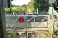 The gates of Teignbridge Level Crossing, just over a mile north west of Newton Abbott, looking towards the former station at Teigngrace (closed 1959). Reviving the closed Teign Valley line north from here to Exeter was one of the options considered as a way of avoiding ongoing difficulties on the coastal route via Dawlish. [Ref query 982] <br><br>[Ian Dinmore 02/10/2015]