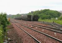 Looking west from Halbeath level crossing in June 2006 towards Queen Margaret station, the platforms of which can just be seen beyond the bridge in the distance. In the siding nearest is a loaded coal train from Hunterston, recently arrived via the Forth Bridge, with its class 66 locomotive having just completed a run-round manoeuvre. The train is now awaiting signals before departing for Longannet power station via Charlestown Junction. The empty train on the far right is on the reverse journey.<br><br>[John Furnevel 02/06/2006]