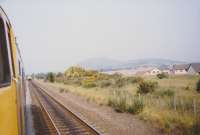 The diverted Birmingham train [see image 58378] has joined the main section of the South Sub at Niddrie West Junction. Another train hauled by a Class 37 loco is held at the signal possibly heading for Millerhill Yard. Arthur's Seat is wreathed in a summer haze in the background.<br><br>[Charlie Niven /07/1989]