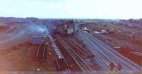 Barassie Junction old and new looking SSW, Monday, 29 November, 1982, the rear end of the freight hauled by 27021 & 20152 swinging round onto Troon loop towards Troon station on the original alignment, the Troon avoiding line closed Saturday, 27 November to allow the junction to be altered (signalboxes at Barassie Junction and Lochgreen Junction, at the south end of the avoiding line, officially closed, Sunday, 28 November).  The new  deviation, temporarily laid behind Barassie Junction Signalbox, opened that morning, hence the shine on the rails already, the track realigned onto a fair curve after the Signalbox had been removed (not particularly clear in what is a rather poor photo are the workmen up on the 'box roof - it didn't last too much longer and was gone before the end of the week.<br><br>[Robert Blane 29/11/1982]